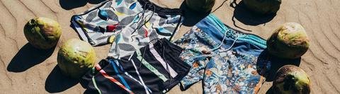 Vissla upcycled coconut boardshorts displayed on sandy beach with coconuts.