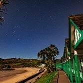 Dan Santillo glass coaster featuring Langland huts under a starry night sky.