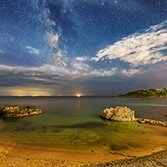 Dan Santillo glass coaster featuring Rotherslade Bay under a starry night sky.