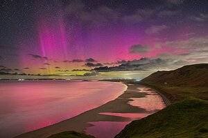 Dan Santilo glass placemat featuring a vibrant Llangennith beach scene with pink and purple auroras.