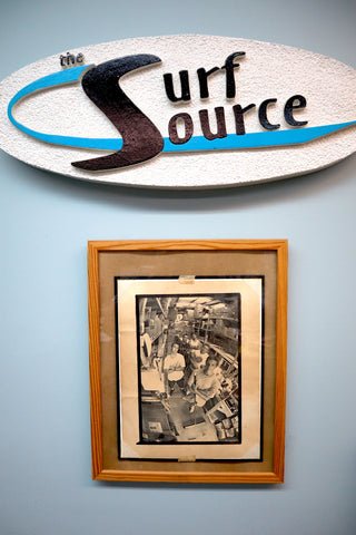 Surf Source article - Founders Story - Origins of surf board distribuler - DING ALL surfboard repair products. This is a photograph of Surf Source signage and frames newspaper article.