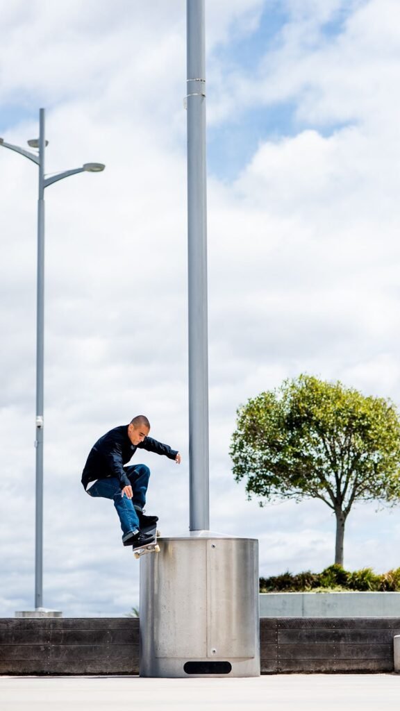 Skateboarder performing a trick on a metal structure under a bright sky.