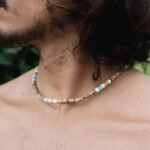 Close-up of Nomad disc necklace with natural and turquoise bead design on a model.