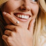 Woman smiling while wearing a silver adjustable shell ring, beach-inspired jewelry.