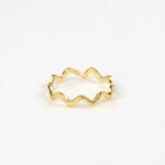 Close-up of gold ripple wave ring on white background.