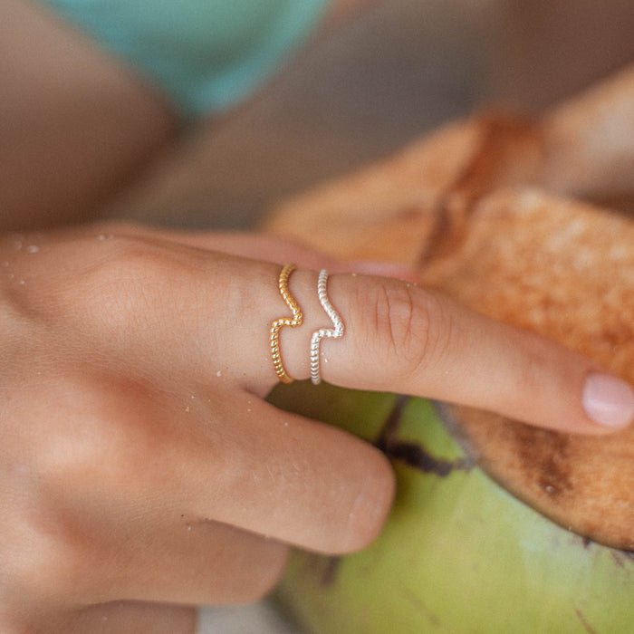 Silver and gold Crest of the Wave ring with adjustable fit, worn on a hand holding a coconut. Handmade jewelry with eco-friendly design.