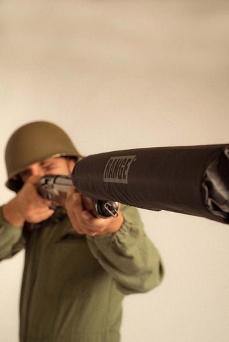 Soldier aiming a rifle with a 'Range' branded barrel cover, symbolizing precision.